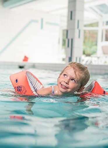 Kind schwimmt im Indoorpool des Hotel Farbinger Hof in Bernau am Chiemsee