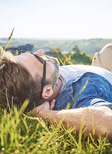 GEW Ferien Mann liegt auf Almwiese und genießt die Entspannung