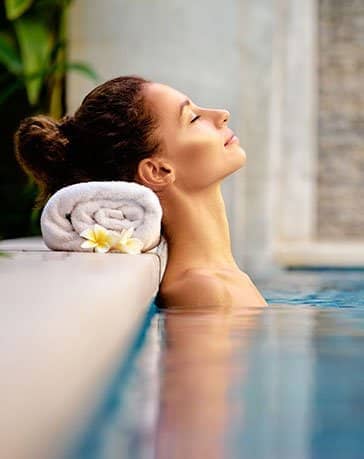 Hotel Farbinger Hof am Chiemsee Junge Frau entspannt sich im Pool des Wellnessbereichs