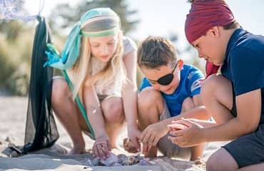 Kinder spielen am Strand mit Muscheln