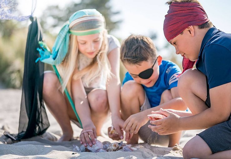 Kinder spielen am Strand mit Muscheln