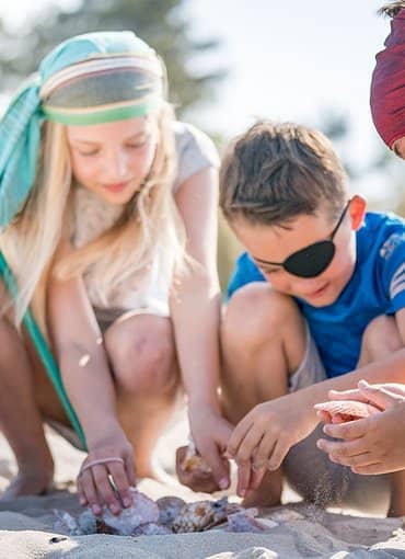 Kinder spielen am Strand mit Muscheln