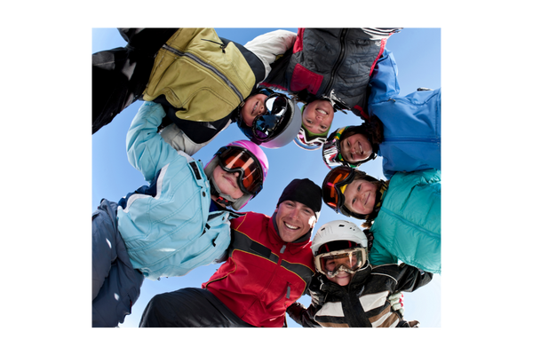 Schifahrer stehen im Kreis blicken runter auf die Kamera und umarmen sich